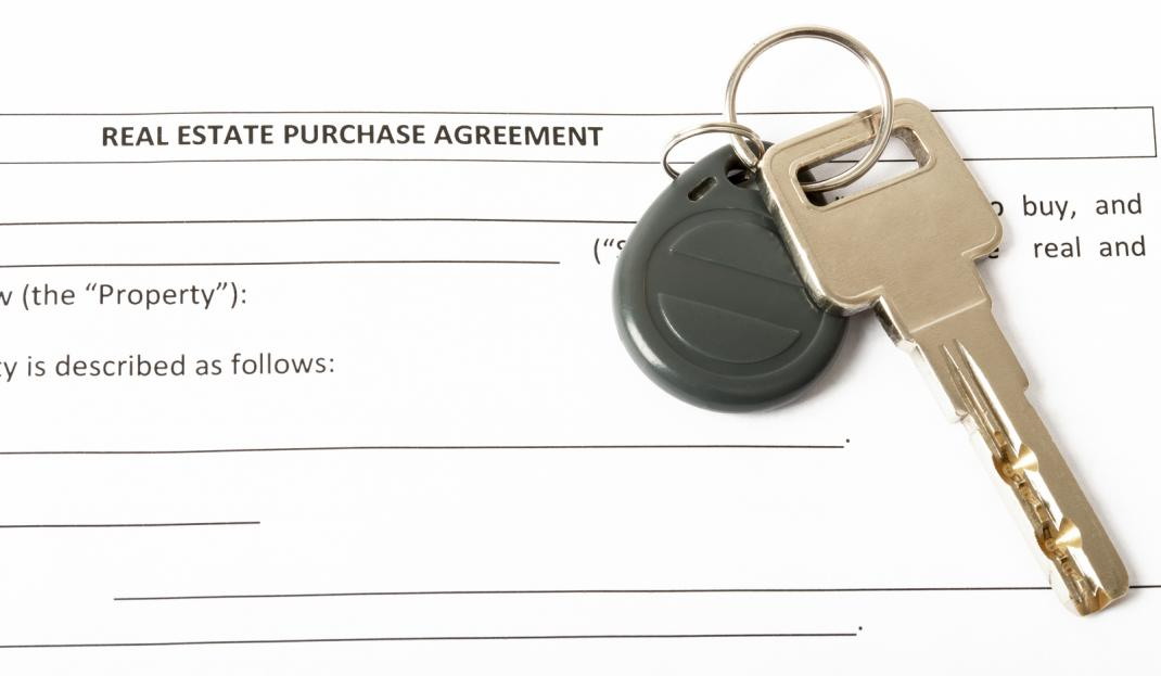 Real estate contract with house key on top